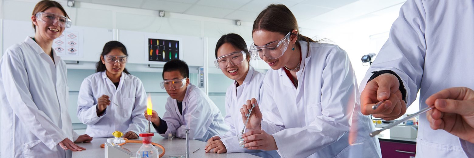 Students and teacher conducting practical in A-Level Chemistry class