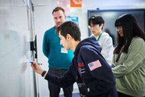 Student working on a writing wall in Maths class at Abbey College Cambridge